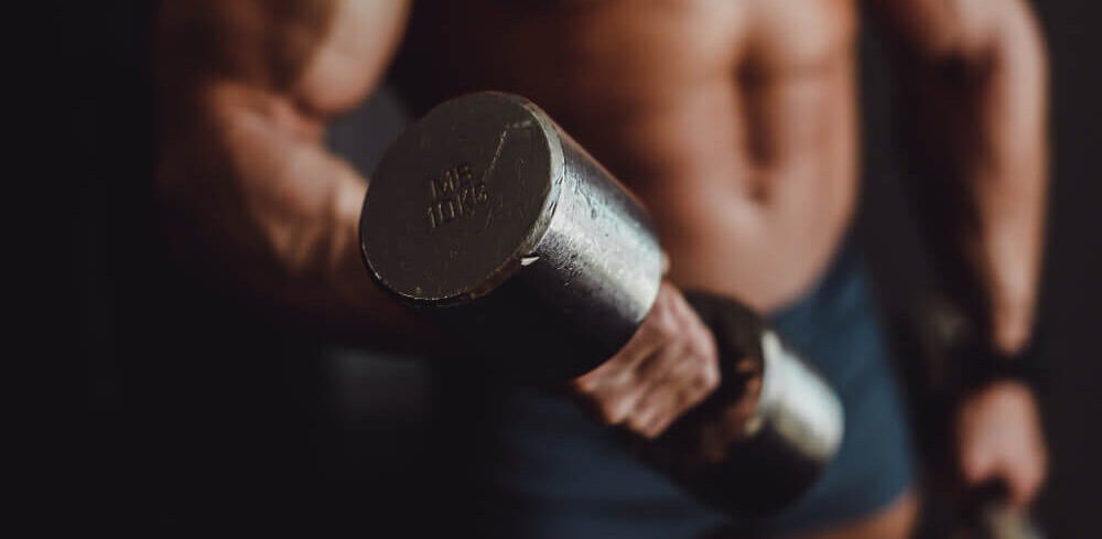 Mężczyzna z umięśnionym torsem trenujący z hantlem – efekty działania LGD‑4033